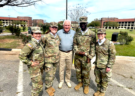 Soldiers in service uniform with a Society representative outdoors on post